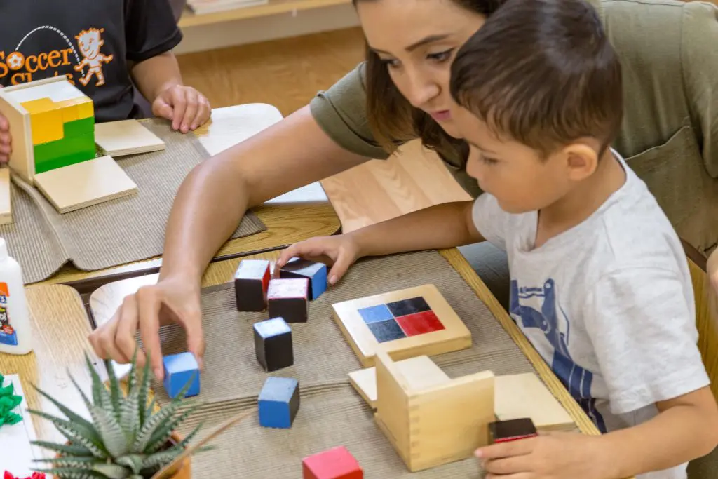 children exploring size relationships with Montessori knobbed cylinders